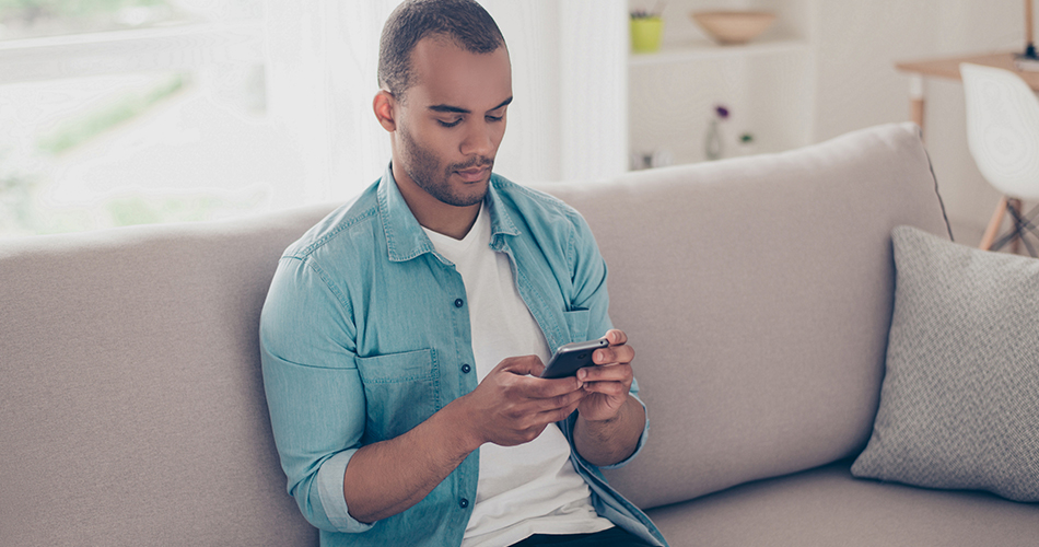 Man sitting on couch looking at iPhone