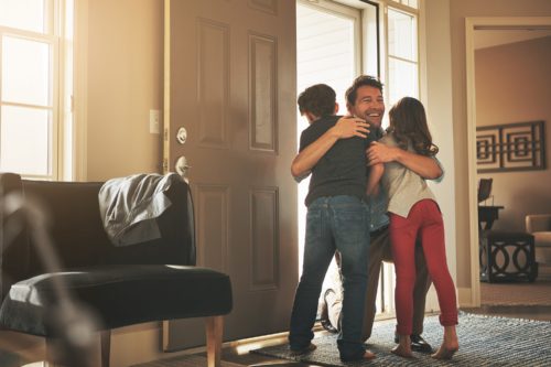Father hugging two children at the door