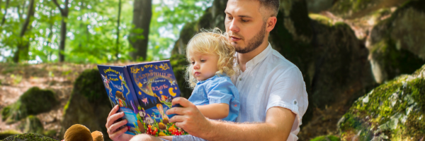 a dad reading to his daughter in the woods