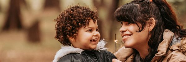 a mom and her son in the outdoors smiling at each-other