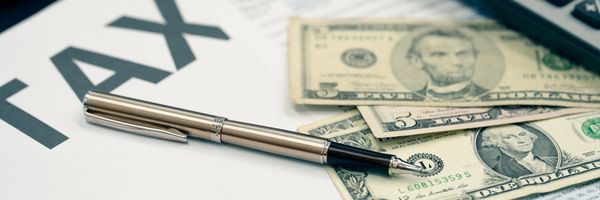 a pen on a paper with money and the word tax written