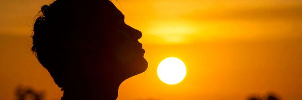 Silhouette of a person in profile facing a bright orange sunset, with the sun low in the sky. From Lawrence Law Firm New Jersey Family Lawyer.