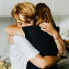 Two people are hugging each other in a kitchen, with one person wearing a white shirt and the other in a black shirt, creating a warm moment reminiscent of family gatherings that Jeralyn Lawrence often cherishes. From Lawrence Law Firm New Jersey Family Lawyer.