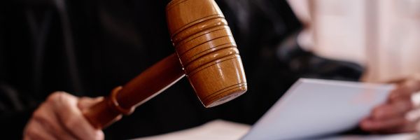 Judge Blee holds a wooden gavel and a document, preparing to make a decision in a courtroom focused on attorney wellness. From Lawrence Law Firm New Jersey Family Lawyer.