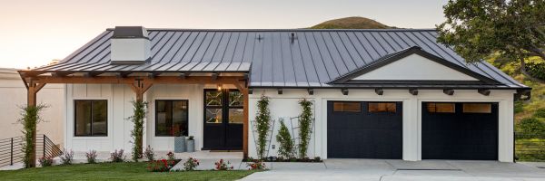 Single-story modern house with a metal roof, white exterior, black-framed windows, double garage, covered entryway, and landscaped front yard—ideal for those starting fresh after an NJ divorce. From Lawrence Law Firm New Jersey Family Lawyer.
