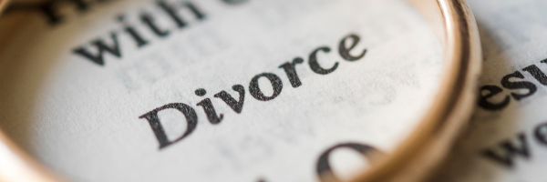 A close-up of the word "Divorce" printed on paper, partially framed by a gold ring, symbolizes the moment many experience when they decide to file for divorce in NJ. From Lawrence Law Firm New Jersey Family Lawyer.