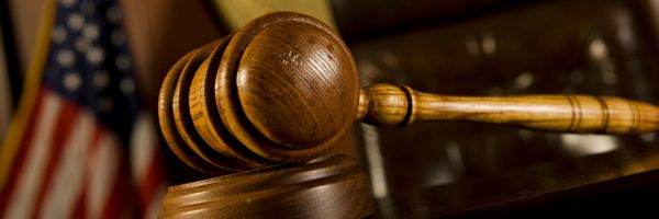 A wooden judge's gavel rests on a sound block with a blurred American flag in the background, symbolizing justice for those looking to File for Divorce in NJ. From Lawrence Law Firm New Jersey Family Lawyer.