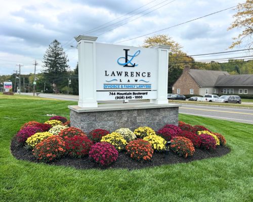 Outdoor sign for Our Firm, Lawrence Law, Divorce & Family Law Firm, located at 744 Mountain Boulevard, with flowers planted around the base and buildings visible in the background. From Lawrence Law Firm New Jersey Family Lawyer.