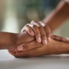 Two hands gently holding another person's hand on a white surface, suggesting support or comfort—an image reflecting the compassionate approach of Jeralyn Lawrence. From Lawrence Law Firm New Jersey Family Lawyer.