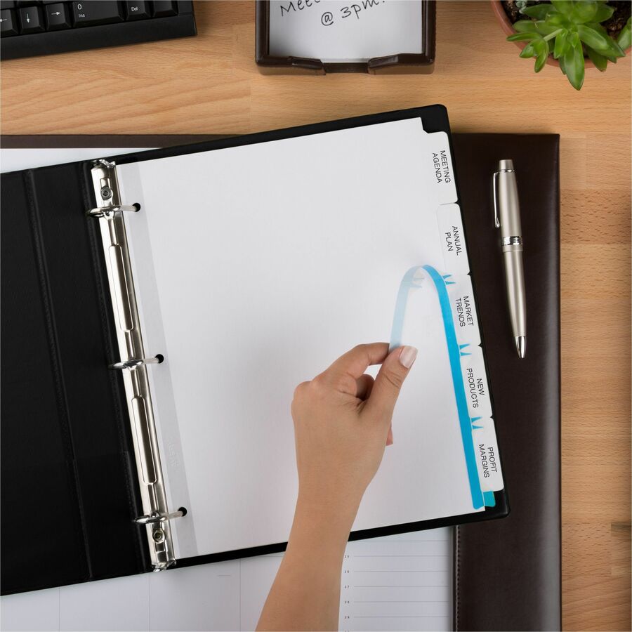 A hand places a blue tab divider labeled "Year-End Divorce Checklist" into a black three-ring binder with labeled tabs on a wooden desk with office supplies. From Lawrence Law Firm New Jersey Family Lawyer.