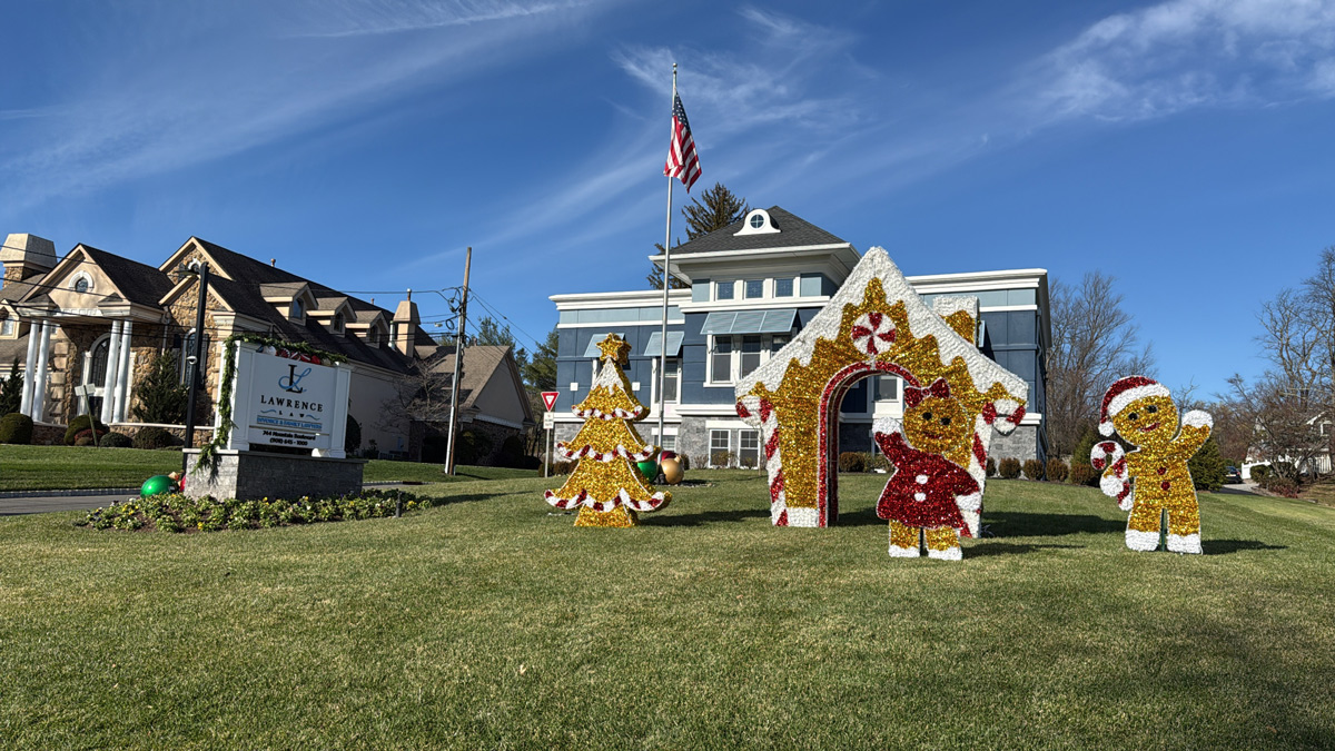 A municipal building with Christmas decorations, including a tree, gingerbread house, and gingerbread figures, displayed on the front lawn under a blue sky—a festive scene reminiscent of Our Firm’s holiday spirit. From Lawrence Law Firm New Jersey Family Lawyer.