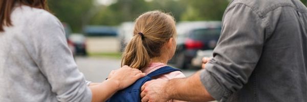 A man helping a girl with a backpack. From Lawrence Law Firm New Jersey Family Lawyer.