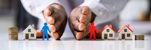 Two hands separate blue and red human figures, houses, and coin stacks, symbolizing the division of assets or property in a financial or legal context. From Lawrence Law Firm New Jersey Family Lawyer.