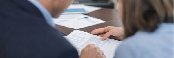 Two people sit at a table reviewing a document together, with charts and papers visible in the background. From Lawrence Law Firm New Jersey Family Lawyer.