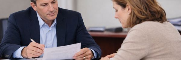 A man and a woman sit at a desk reviewing a document together in an office setting. From Lawrence Law Firm New Jersey Family Lawyer.